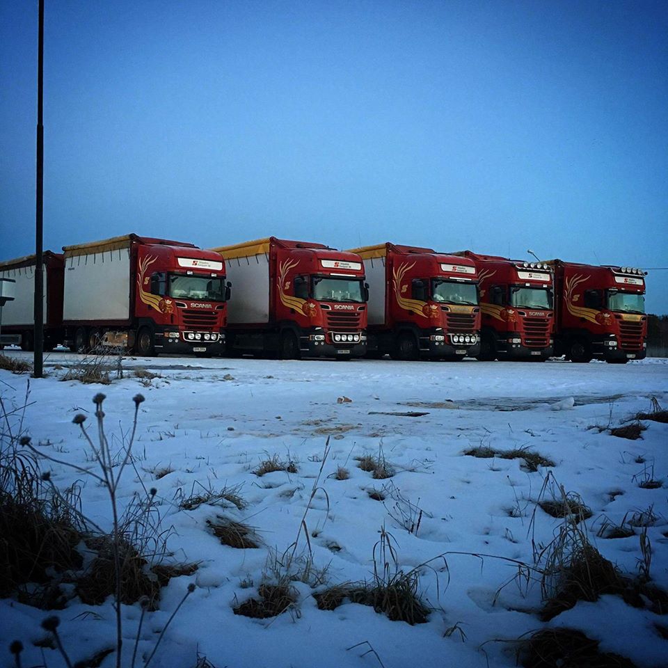 Fem Scania-ekipage uppställda i vinterlandskap i skymning