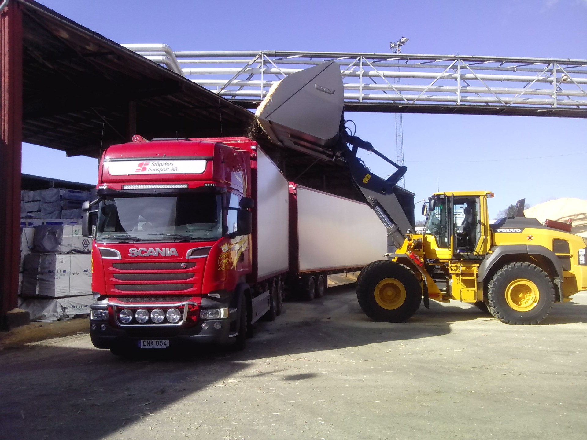 Scania lastas med flis av Volvo hjullastare